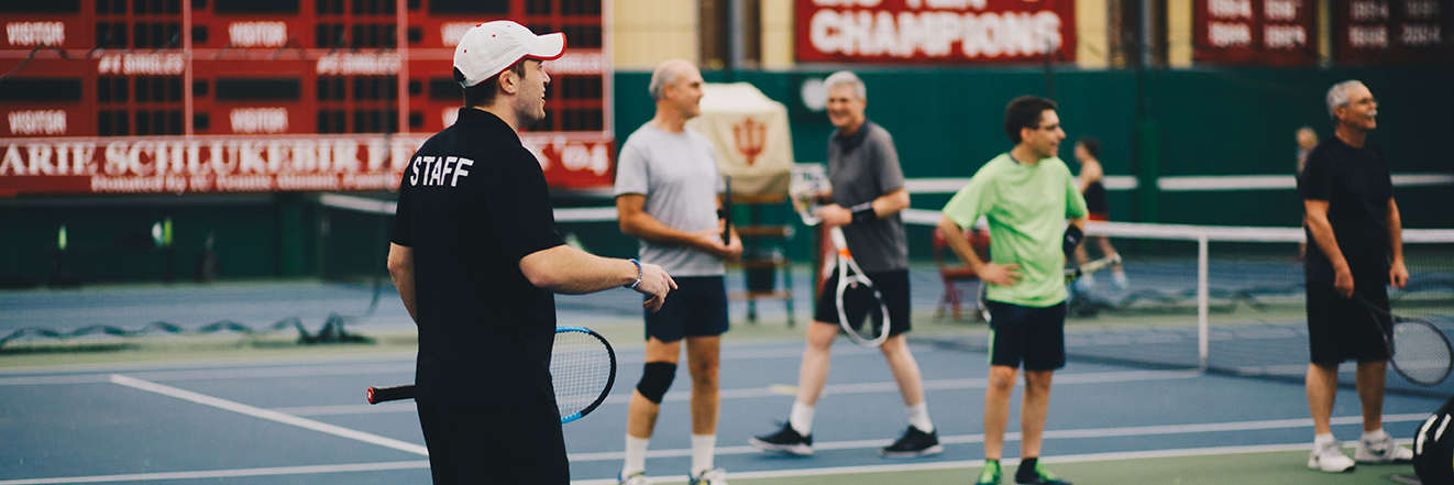 Tennis instructor leading a group of players.