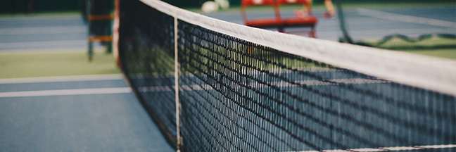A tennis net stretches across the middle of a court.